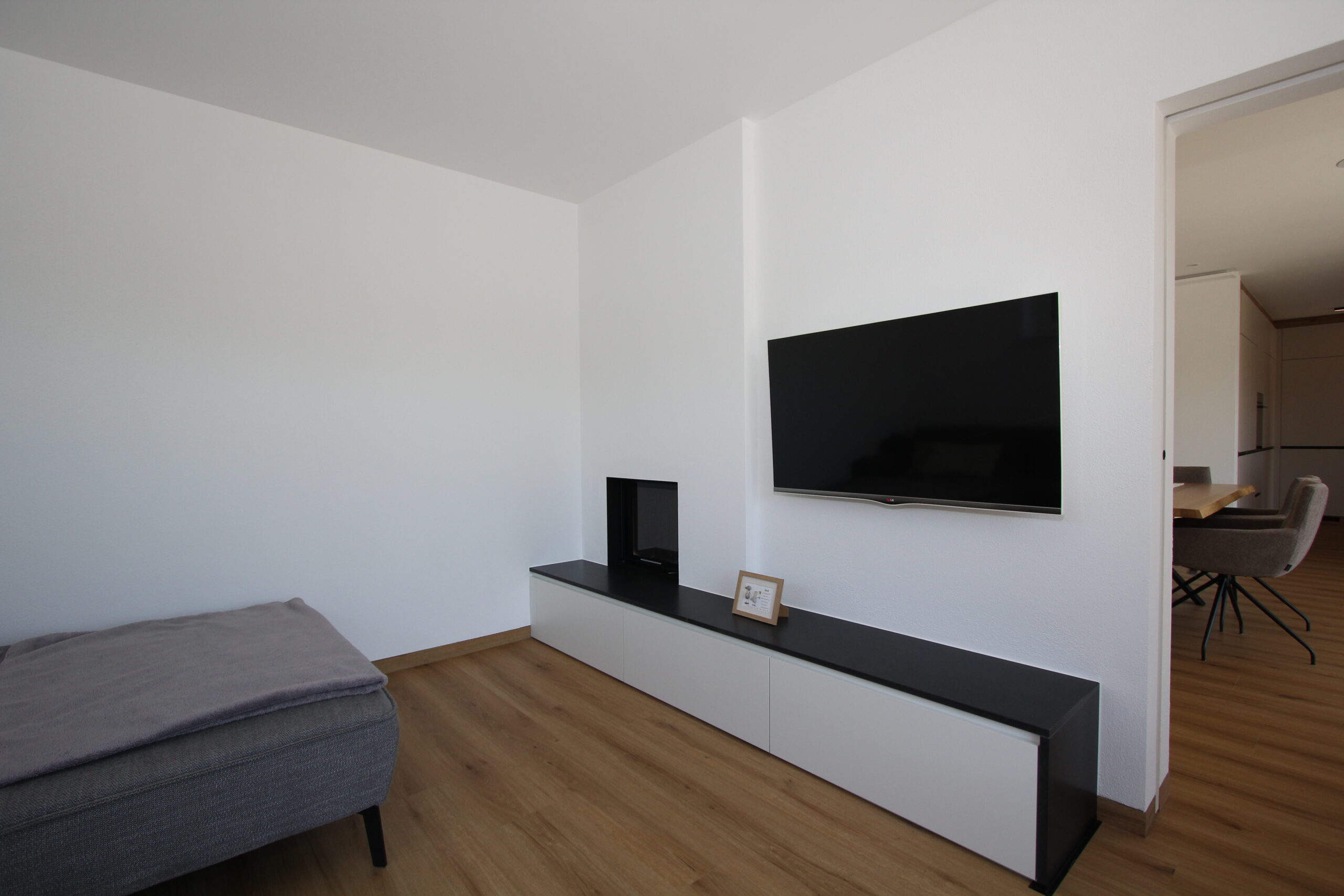 Modernes Wohnzimmer in Eiche und Weiß mit TV-Verbau, Steinumrandung und Schubladenverbau