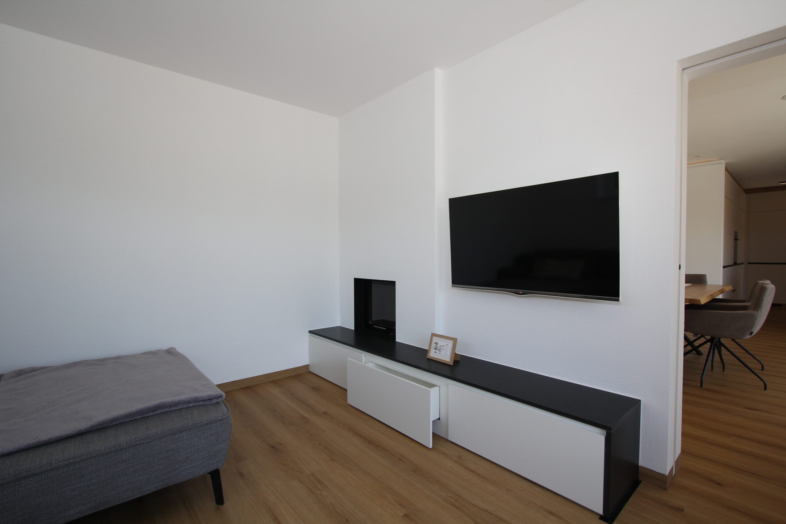 Modernes Wohnzimmer in Eiche und Weiß mit TV-Verbau, Steinumrandung und Schubladenverbau